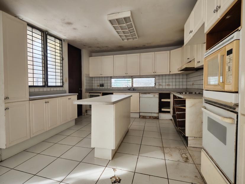La cocina antes: gabinetes gastados, techo manchado y piso dañado